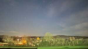 Night time view overlooking Durrow from The Harps GAA field. It's a clear sky and there are streetlights aplenty and the Church is illuminated with a soft yellow glow from floodlights.