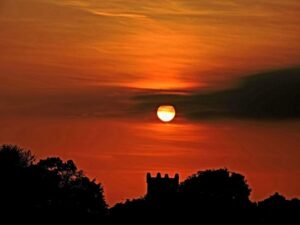 A dramatic red sunset over Durrow with the Church Of Ireland's steeple visible behind dark silhouettes of trees. Photo by Andrew Walsh