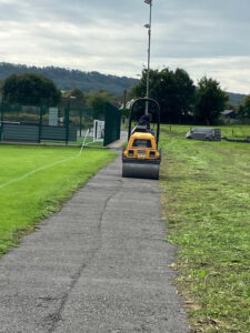 At the Lions AFC grounds, a roller machine constructs a new gravel footpath alongside the main soccer pitch.