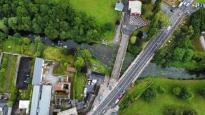 Overhead view of the Old Bridge and the New Bridge in Durrow by Bob's Bar. There are many people in canoes on the River Erkina flowing by. Photo: Pat Farrell