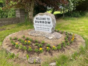 Welcome to Durrow sign with flowers beneath it planted by the Tidy Towns group.